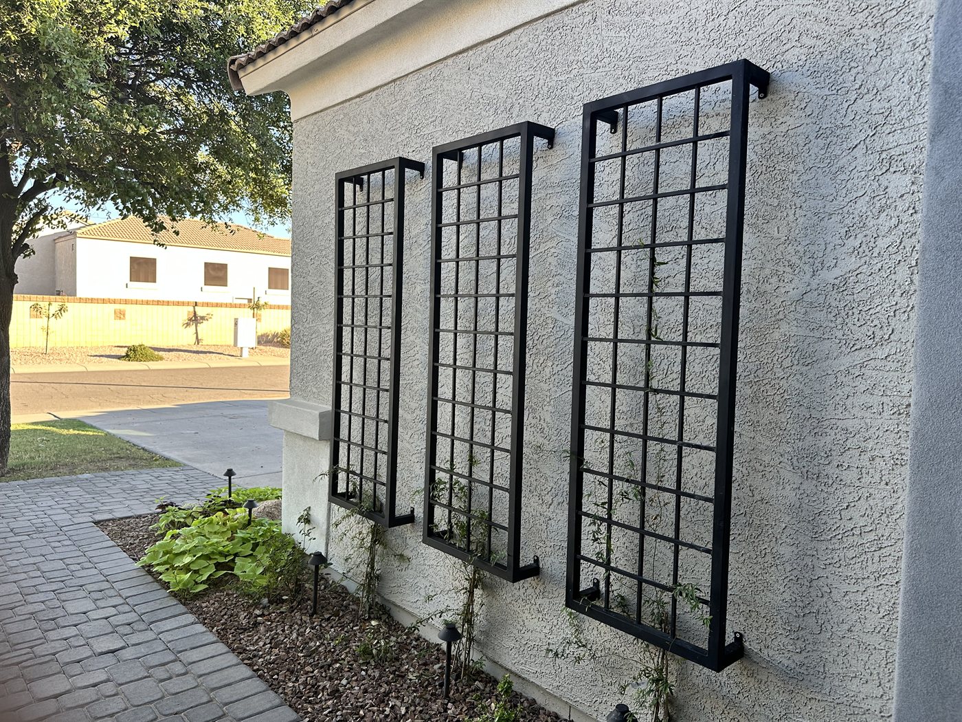 Three tall window-grid trellis panels along a stucco wall